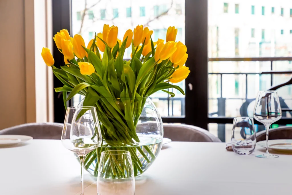 yellow tulips in a glass globe vase on dining table